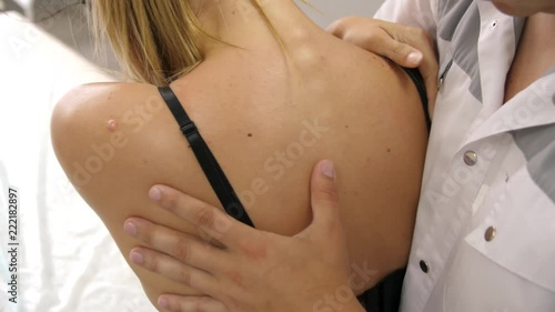 Manual therapist massaging and examining a young woman stretching her spine. The chiropractor adjusts the patient's vertebrae by pressing her fingers