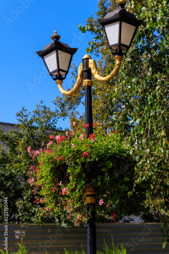 Fototapeta Naklejka Na Ścianę i Meble -  Street lantern decorated with geranium flowers in flowerpot
