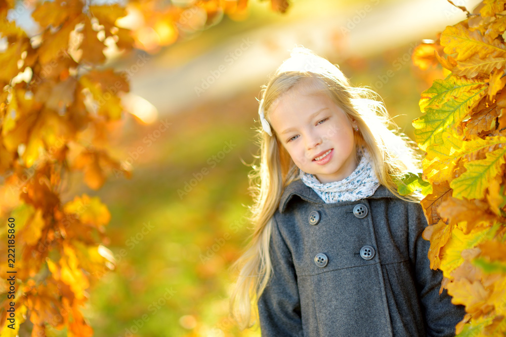 Cute little girl having fun on beautiful autumn day. Happy child playing in autumn park. Kid gathering yellow fall foliage. Cute little girl having fun on beautiful autumn day. Happy child playing in autumn park. Kid gathering yellow fall foliage.