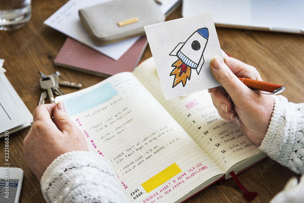 Naklejka premium Hand holding a rocket launch drawing on a sticky note