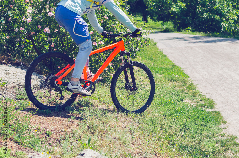 Naklejka premium A cyclist on an orange bike is driving off-road