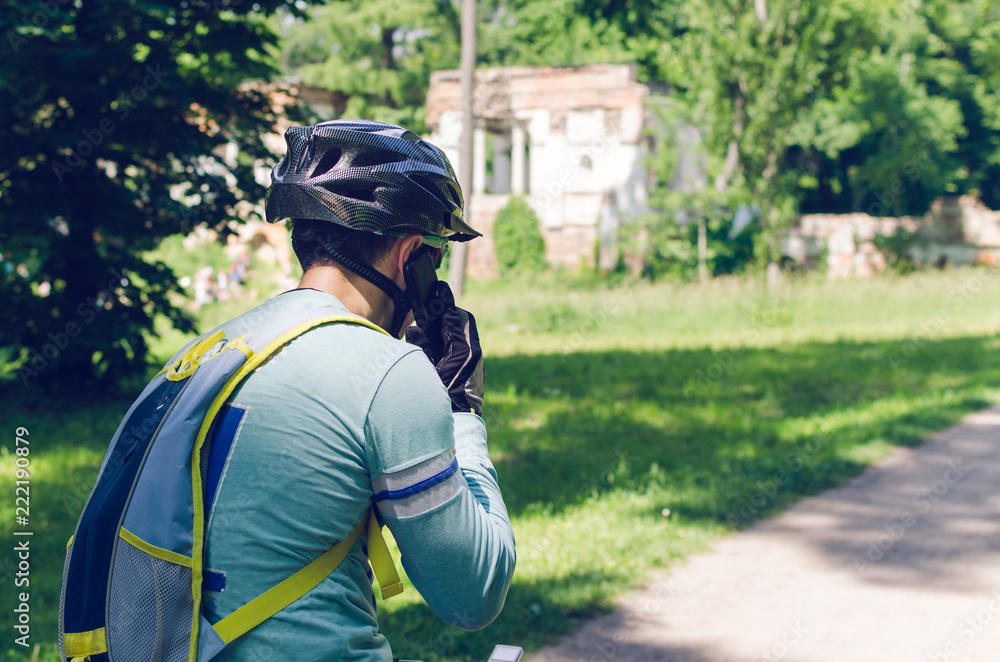 Obraz premium A cyclist in a helmet is riding in the park and talking on the phone