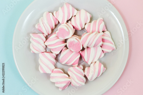 CLose up, top view photo of tasty yummy pink and white marsmallows on half blue half pink background. Minimal style, soft colors photo