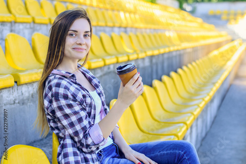 Φωτογραφία Smiling happy woman drinking coffee and watching the match at the stadium