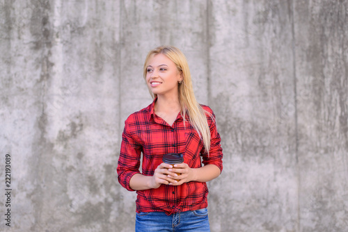 It's time for takeaway coffee! Young smiling girl enjoying coffee for breakfast. She is dressed in red checkered shirt and jeans