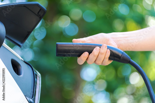 Person charging an electric vehicle with green background