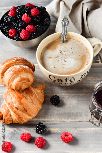 Breakfast at the European hotel: coffee with milk and croissants, jam and fresh raspberries and blackberries on a wooden table. on the Cup inscription in French (mocha coffee, coffeewith milk) photo