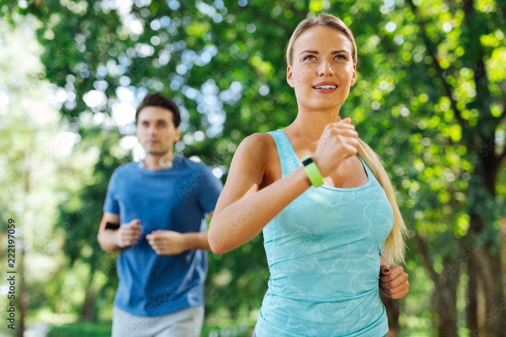 Obraz premium Sports exercise. Delighted nice woman being in the park while jogging in the morning