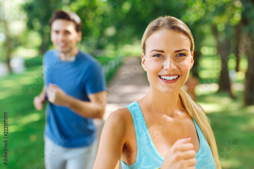 Positive mood. Happy nice woman smiling while enjoying the run in the park