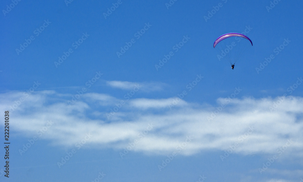 A paratrooper flies against a blue cloudy sky A paratrooper flies against a blue cloudy sky
