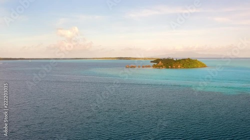 drone flight over the ocean in front of Bora Bora. Different blues in the water, small Motu / Island in front. A small boat is crossing the scene. photo