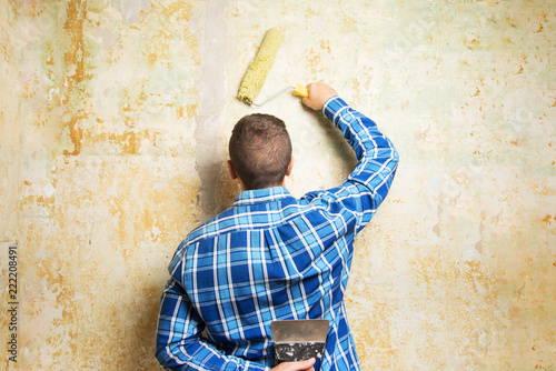 A man with a roller and a construction spatula is ready for repair. photo