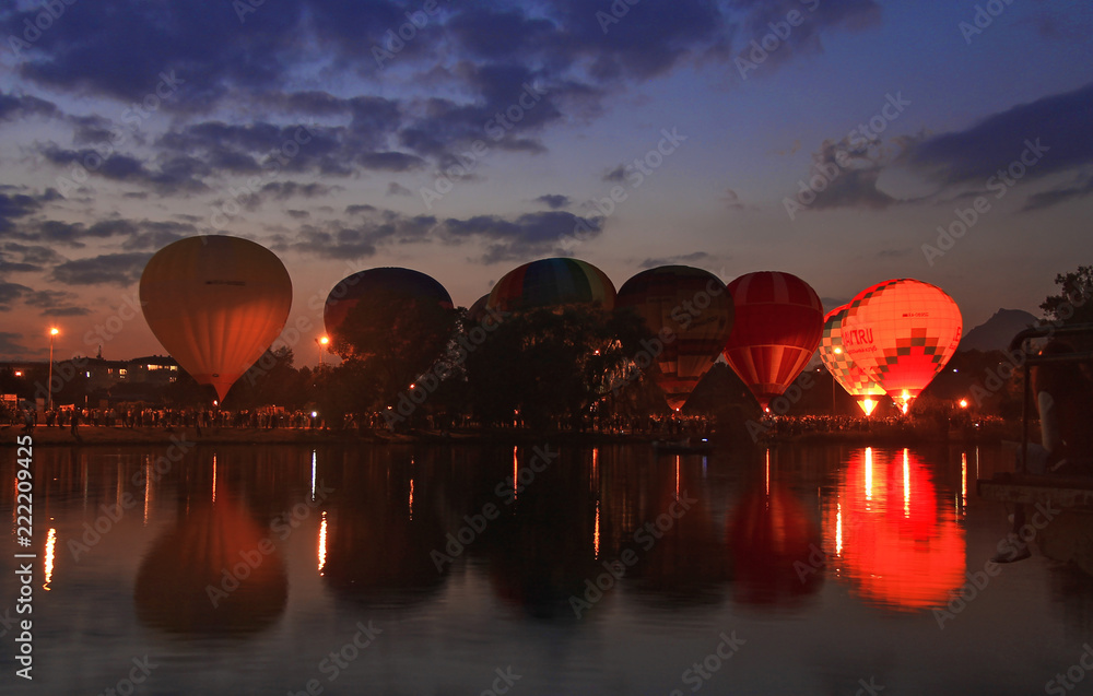 Fototapeta premium Hot air baloons flying in the evening sky near the lake