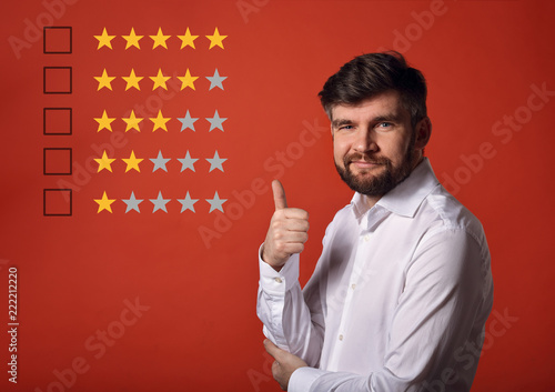 The best rating, evaluation, online rewiew. Happy bearded business showing the hand thumb up  in white shirt on red background with empty space background photo