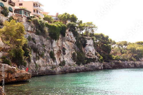 Impressive sea cliffs and people jumping in the sea at Porto Cristo, Mallorca, Spain
