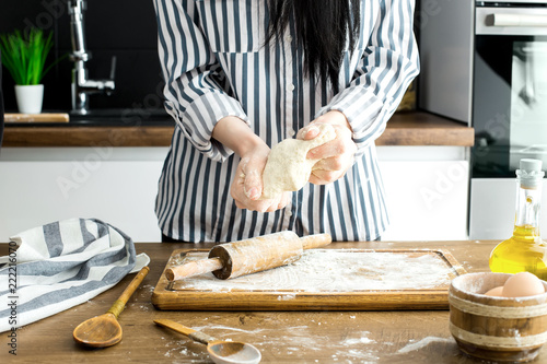 Female hands making dough on kitchen background