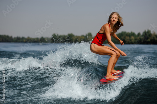 Pensive blonde girl riding on the red wakeboard