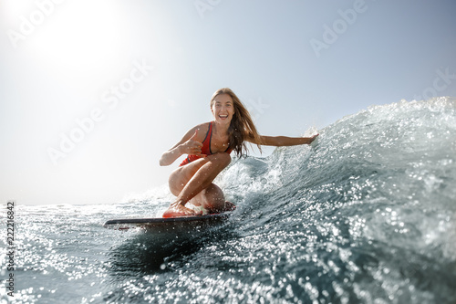Attractive blonde girl standing on the wakeboard and looking at camera