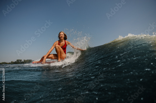 Smiling blonde girl sitting on the wakeboard and looking at camera