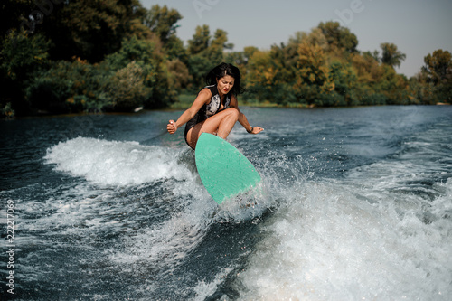 Brunette girl jumping on the wakeboard on the lake