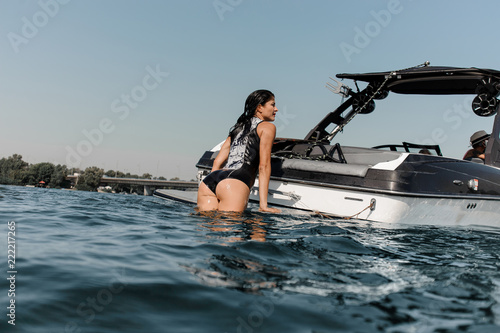 Obraz na plátně Attractive girl climbing on the motorboat on the lake