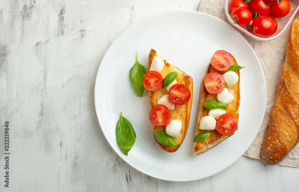 Bruschetta with tomatoes, mozzarella cheese and basil in a white plate. Traditional Italian snack or snack, antipasto. With space for writing