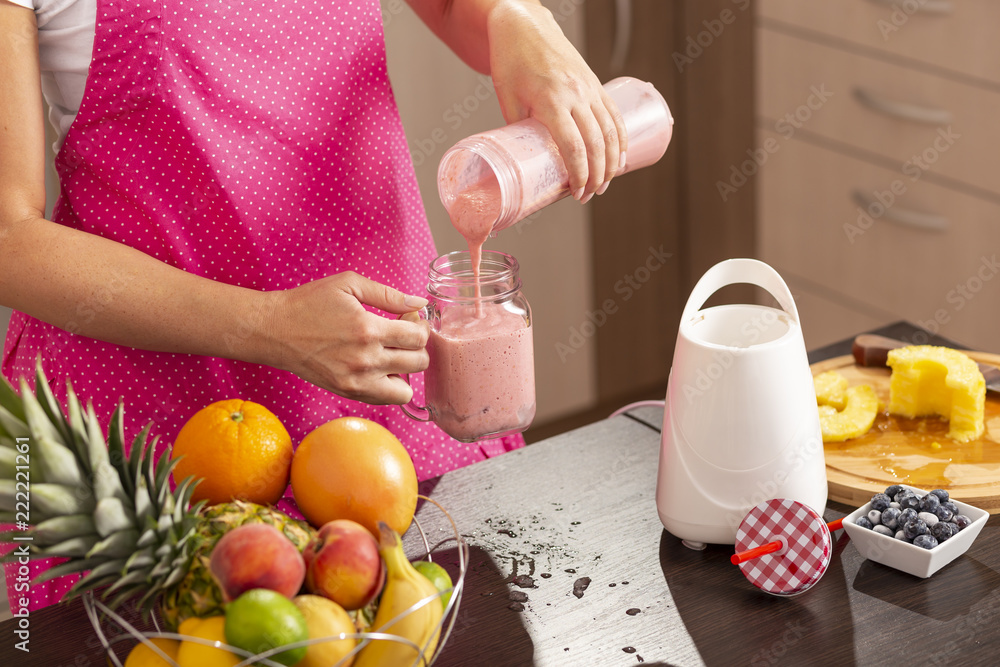 Woman pouring raspberry smoothie in a jar