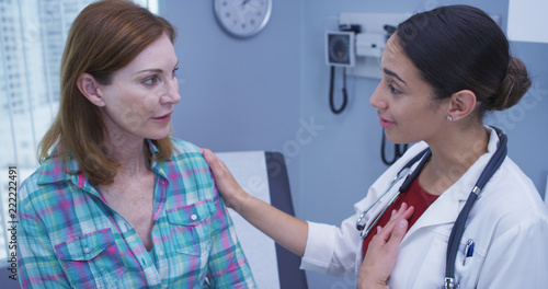 Young latina doctor telling senior patient the good news about her health. Portrait of young doctor with positive attitude towards middle aged patient indoors medical clinic
