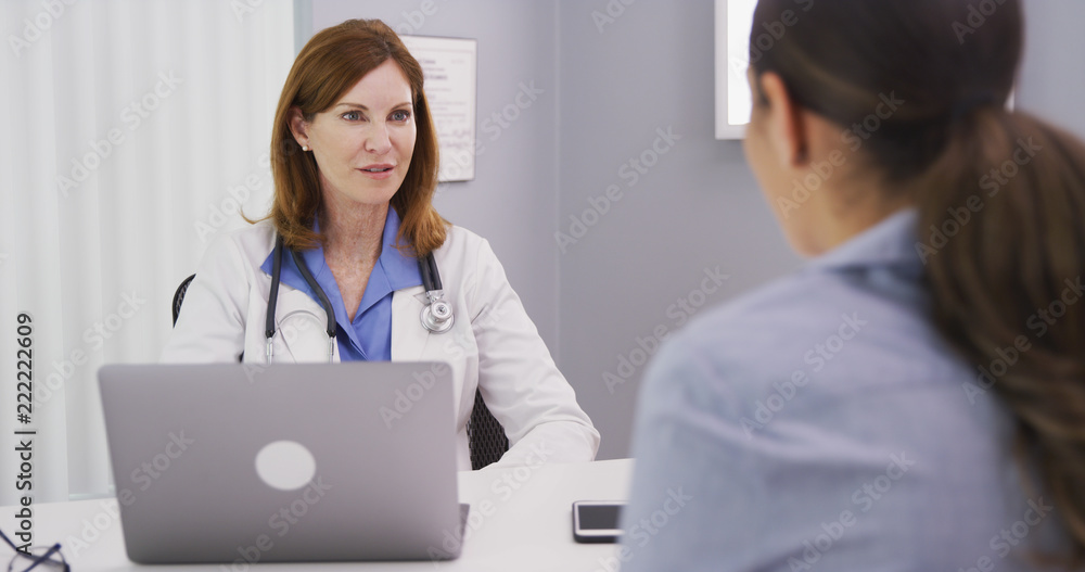 Professional caucasian doctor discussing with young female patient about issues surrounding future surgery. Young patient consulting with medical doctor over her health condition Professional caucasian doctor discussing with young female patient about issues surrounding future surgery. Young patient consulting with medical doctor over her health condition