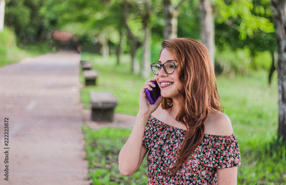 smiling woman talking on the cell phone while waiting sitting in the park