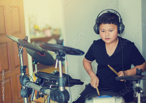 Obraz na plátně Asian boy put black tshirt and headphone learning and play electronic drum with