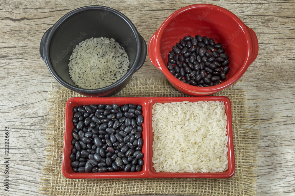 rice and black beans crude in red container on wooden background rice and black beans crude in red container on wooden background