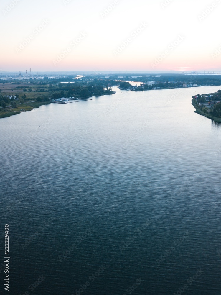 Fototapeta premium Beautiful sunset over estuary of Vistula river in Gdansk. Summer sunset over sea and river and small village.