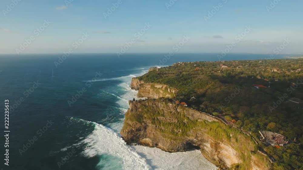 Aerial view of Traditional Hindu temple Pura Uluwatu. Rocky coast with surf the waves off the at sunset, Bali,Indonesia. Waves crushing rocky shore. Seascape, rocks, ocean. 4K video. Travel concept Aerial view of Traditional Hindu temple Pura Uluwatu. Rocky coast with surf the waves off the at sunset, Bali,Indonesia. Waves crushing rocky shore. Seascape, rocks, ocean. 4K video. Travel concept