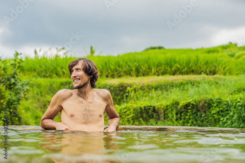 Man tourist in Belulang Hot Springs in Bali on the background of rice terraces photo