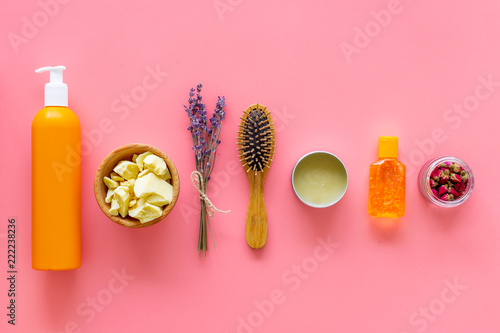 Cosmetics for hair care with jojoba, argan or coconut oil. Bottles and pieces of oil on pink background top view pattern