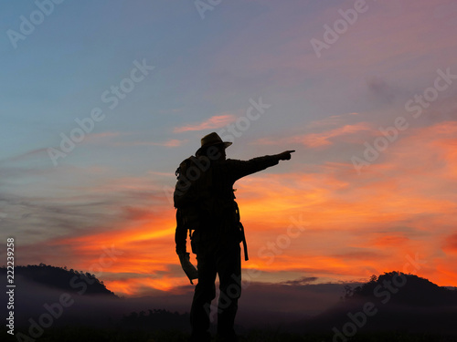 silhouette male tourist with backpacks stand to the top of mountain and enjoying sunrise. freedom and active lifestyle concept.