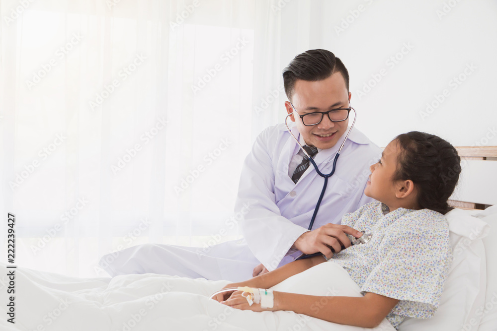 Fototapeta premium Professional doctor wearing white coat using stethoscope to examine kid patient on bed in hospital background.Concept of disease treatment and health care in hospitals.