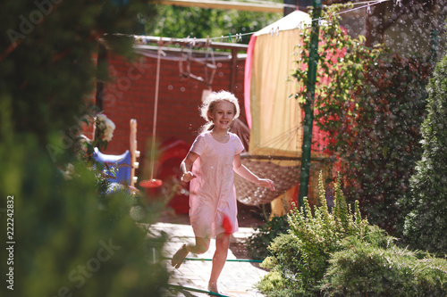 A cheerful charming seven-year-old girl enjoys a sunny summer morning and has fun in the garden at home