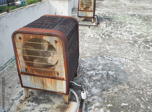 Rusty heavy duty industrial size air compressor machine units on roof deck.