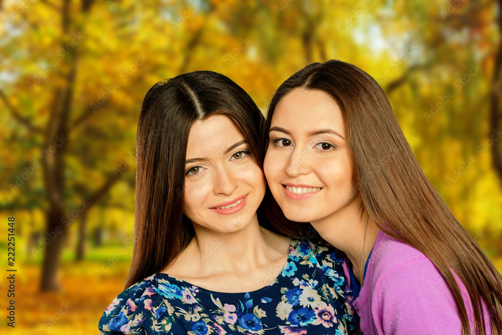Obraz premium Two cheerful girls twins, in the street autumn park