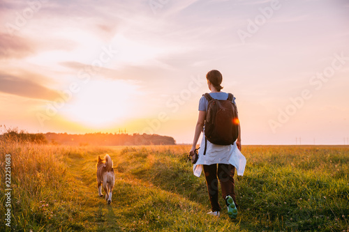 Obraz na płótnie Young Woman Backpacker Walking With Dog In Summer Meadow Grass D w salonie