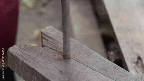 HD video footage showing an unrecognizable carpenter drilling a hole into a piece of wood with his electric drill