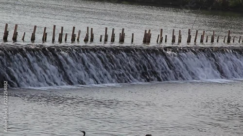 HD video footage showing water overflowing from a small dam or floodway blocking a river
