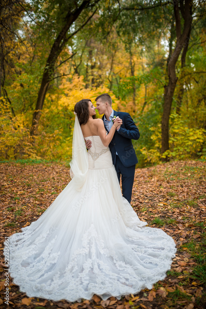 Groom and bride in autumn yellow leaves park. What to wear on the autumn wedding. Full length Groom and bride in autumn yellow leaves park. What to wear on the autumn wedding. Full length
