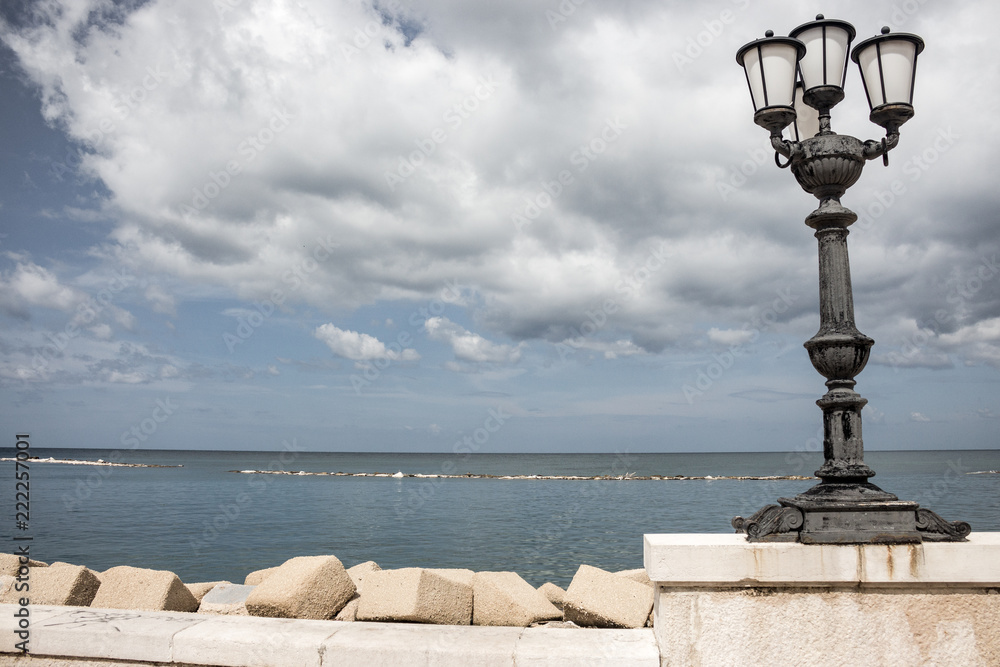 Seaside with iron street lamp on cloudy day muted colors. Adriatic seascape. Italian panoramic coastline. Italian south background. Street decoration in Bari, Italy. Travel and vacation concept.