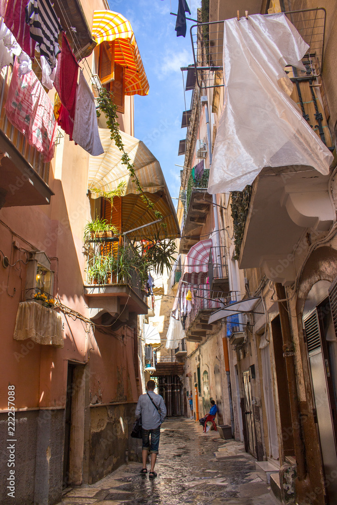 Narrow street with hanging clothes on balconies in south of Italy, Bari.  Dying laundry on balcony. Italian southern architecture. Summer shadow on  streets. Travel concept. Mediterranean houses. Stock Photo | Adobe Stock