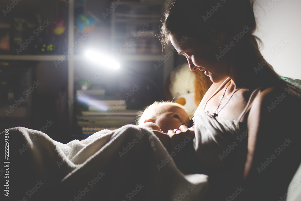 Young beautiful mother breastfeeding her newborn baby boy at