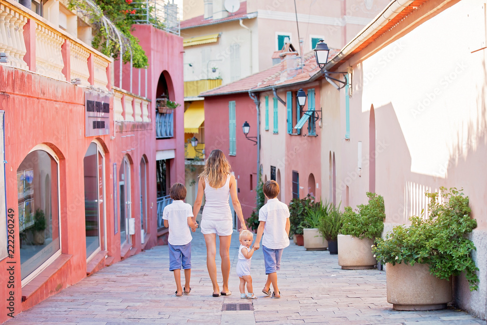 Φωτογραφία Young mother, holding her children hand in hand, walking on a street in Villefra