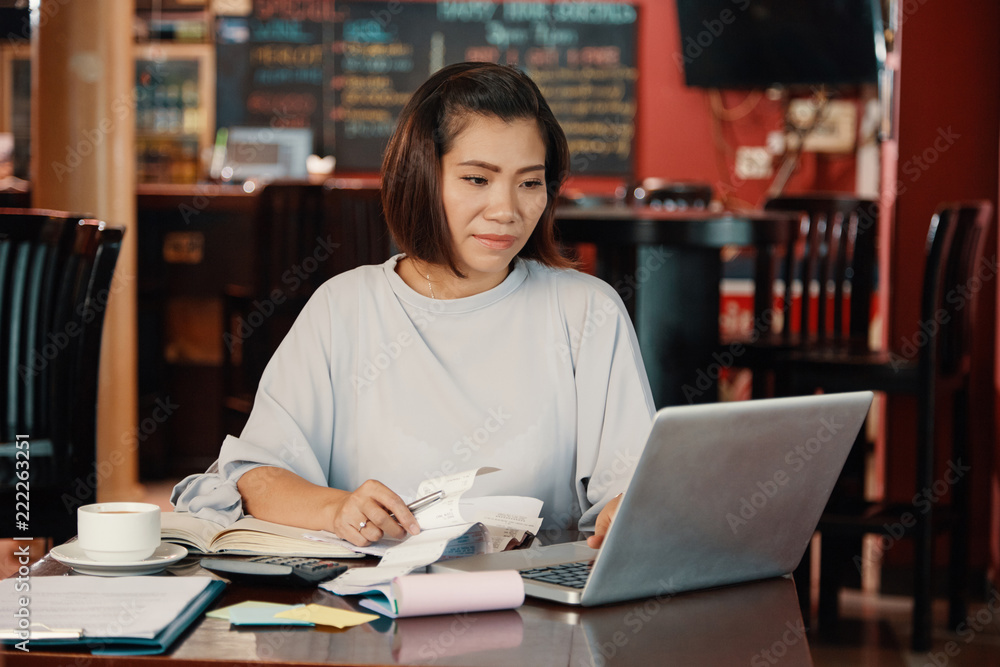 Female pub owner working on laptop and paying bills online Female pub owner working on laptop and paying bills online